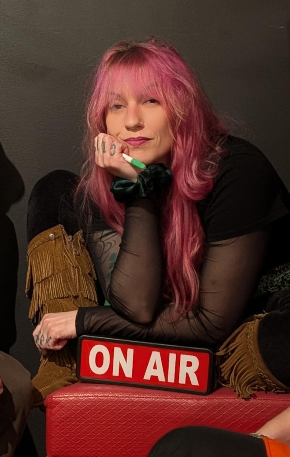 Michele Rowley seated beside an illuminated On Air sign